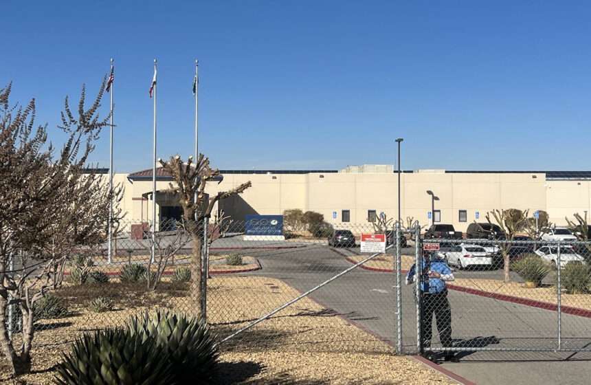 guard closing gate outside Adelanto immigrant detention facility
