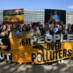 large group of people in protest, banners "Kick Industry Out" & "People Over Polluters"