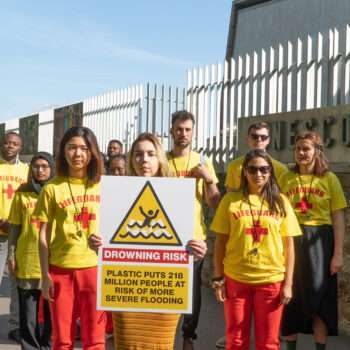 group of people in yellow lifeguard shirts, sign "Drowning Risk"