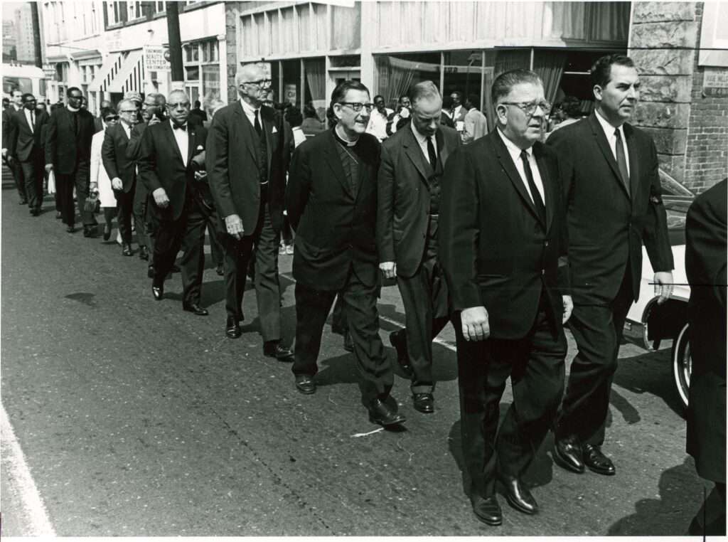black and white photo of men in suits walking in a funeral procession