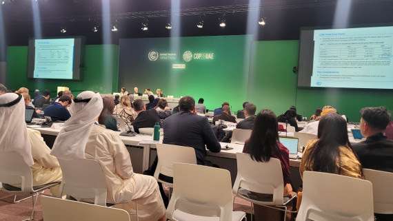 many people in an auditorium, projection screen "COP 28 UAE"