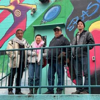 four people standing in front of colorful mural