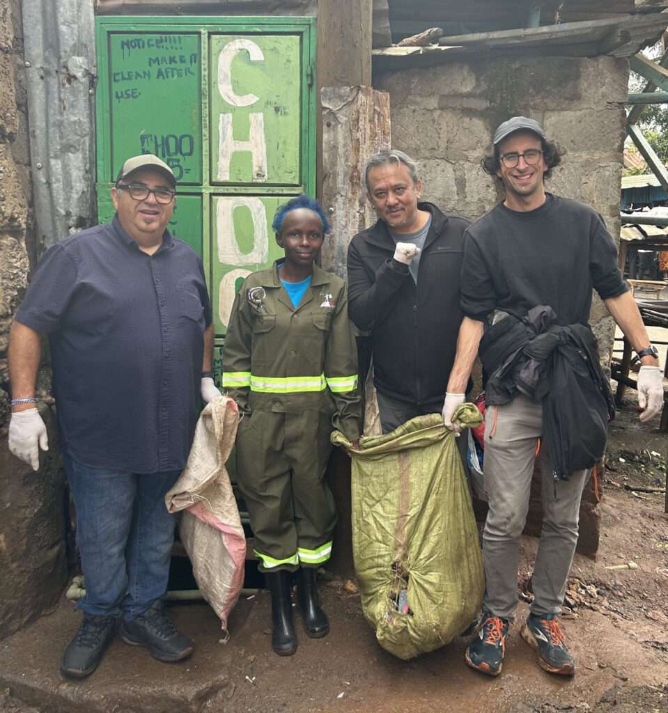 four people posing with waste collection bags in slum street
