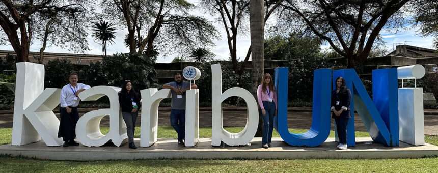 five people standing within a large 3D sign "karibUNi"