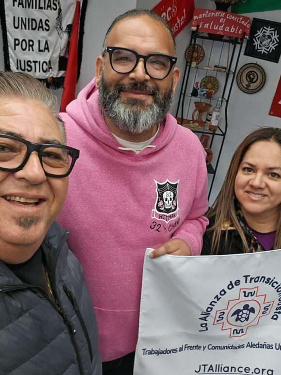 three people posing with a banner "La Alianza de Transicion Justa"